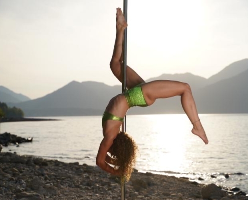 Eine Polerina an der Pole Stange, sie trägt einen grünen Zweiteiler in metallic und mit Pailletten